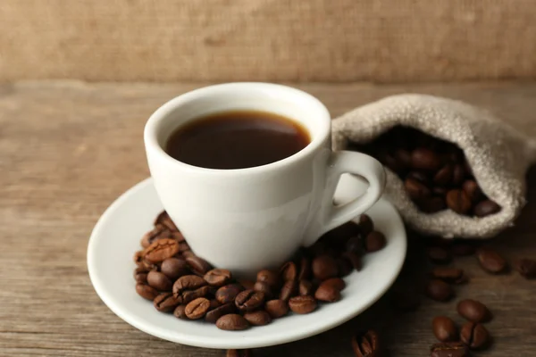 Taza de café con frijoles sobre fondo rústico de madera — Foto de Stock