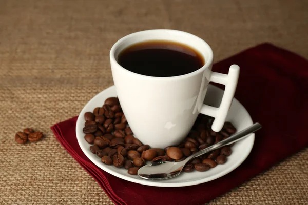 Tasse Kaffee mit Bohnen auf rustikalem Holzgrund — Stockfoto