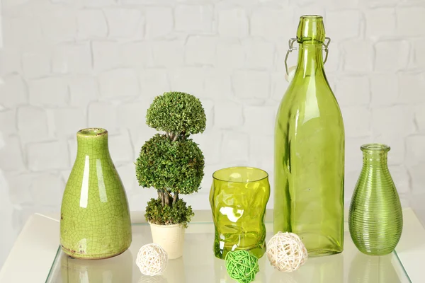 Interior with decorative vases and plant on table top and white brick wall background — Stock Photo, Image