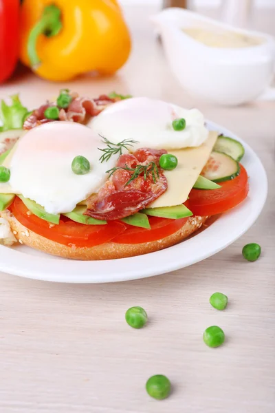 Sandwich mit pochierten Eiern, Speck und Gemüse auf Teller auf Holzgrund — Stockfoto