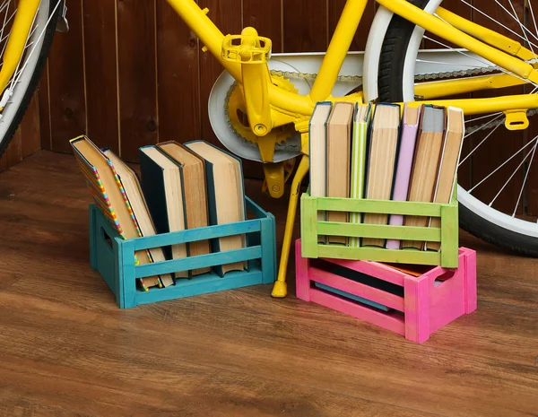 Bicycle with books in crate on wooden wall background — Stock Photo, Image