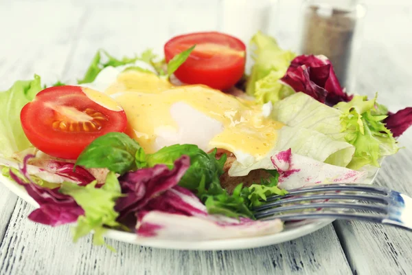 Toast with egg Benedict and tomato on plate on wooden table — Stock Photo, Image