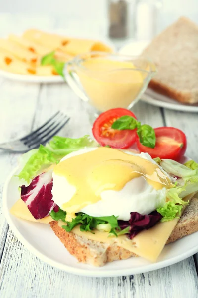 Toast with egg Benedict and tomato on plate on wooden table — Stock Photo, Image