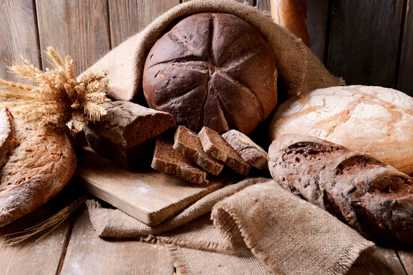 Verschillende brood op tafel op houten achtergrond — Stockfoto