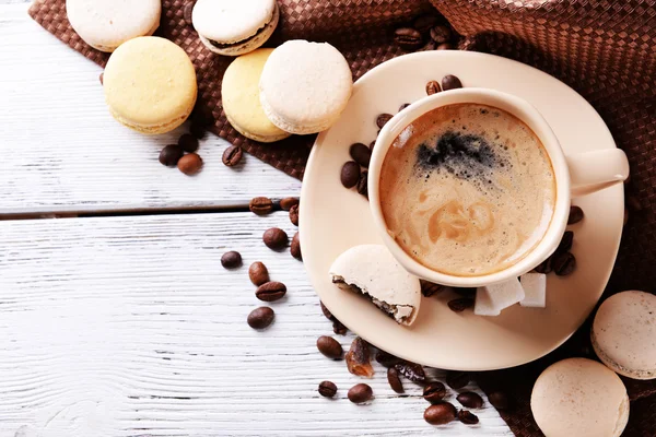 Macaroons coloridos suaves e café na caneca na cor de fundo de madeira — Fotografia de Stock