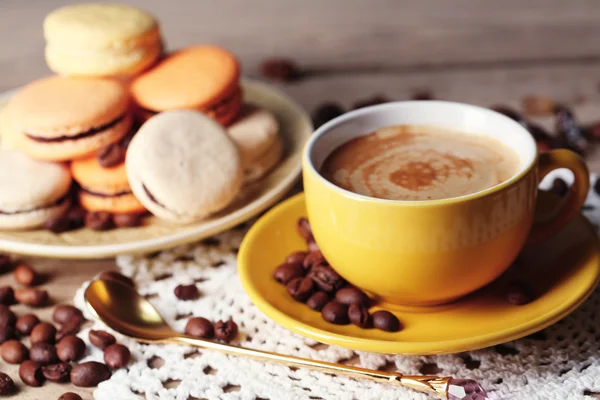 Macarons colorés doux et café en tasse sur fond de table en bois — Photo