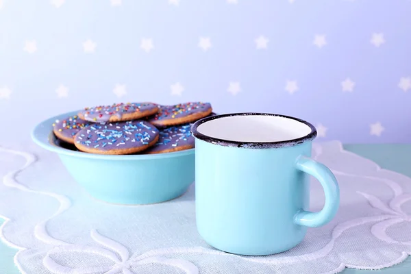 De punten van de kom van geglazuurde cookies en mok van melk op servet en kleur achtergrond — Stockfoto