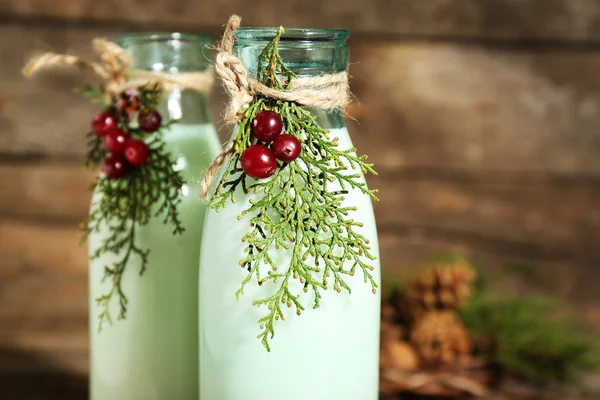 Bottles of fresh milk with natural decor, on wooden background — Stock Photo, Image