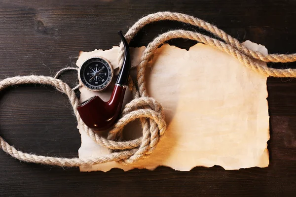 Nature morte marine tuyau, boussole, corde et feuille de papier sur fond en bois — Photo