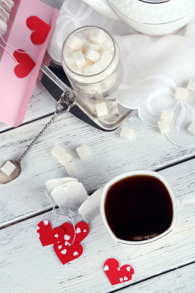 Heart shaped teabag tags, box, teacup on wooden background — Stock Photo, Image