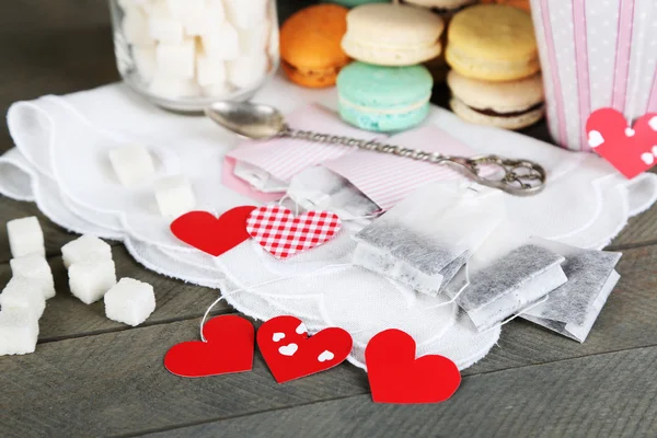 Tag bustina di tè a forma di cuore, macaron e tazza di tè su sfondo di legno — Foto Stock