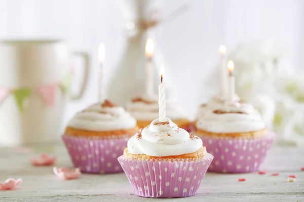 Deliciosos cupcakes de aniversário na mesa no fundo claro — Fotografia de Stock