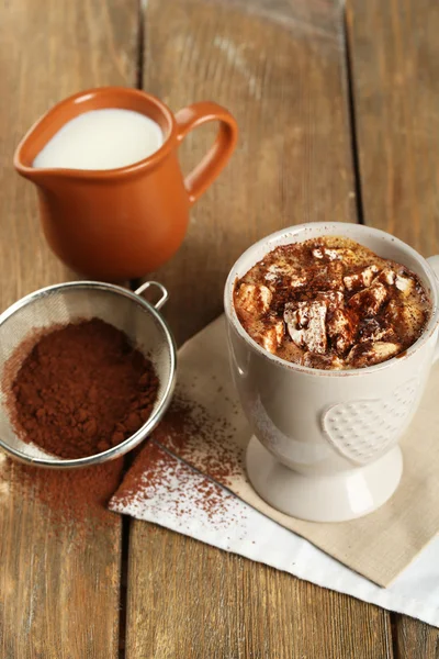 Taza de café caliente con malvavisco y taza de leche con colador de cacao sobre servilleta y fondo rústico de tablones de madera — Foto de Stock