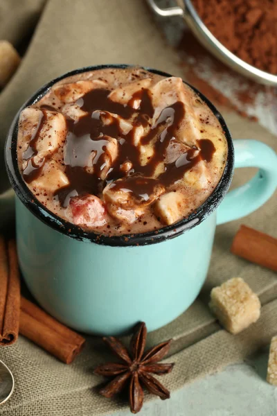 Taza de café caliente con malvavisco en tela con azúcar en bulto, canela, anís estrellado y tinte de cacao sobre fondo de tablones de madera de color — Foto de Stock