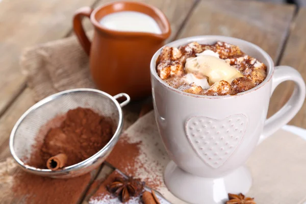 Taza de café caliente con malvavisco y taza de leche con canela, anís estrellado y colador de cacao sobre servilleta y fondo rústico de mesa de madera — Foto de Stock