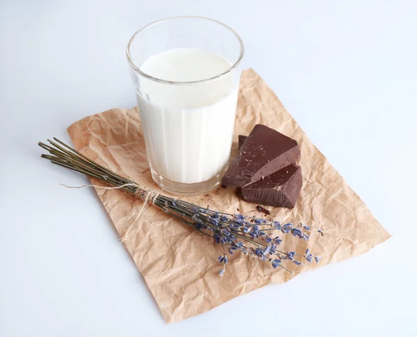 Glass of milk with chocolate chunks on sheet of crumpled paper isolated on white — Stock Photo, Image