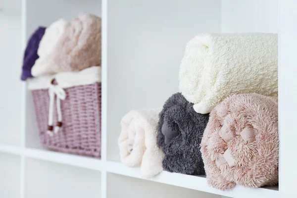 Handdoeken met rieten mand op plank van rack achtergrond rolde — Stockfoto