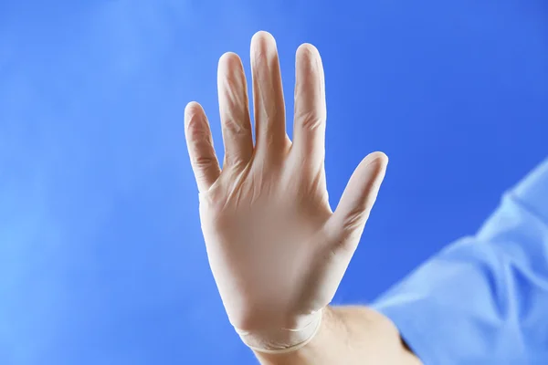 Doctor hand in sterile gloves on blue background — Stock Photo, Image