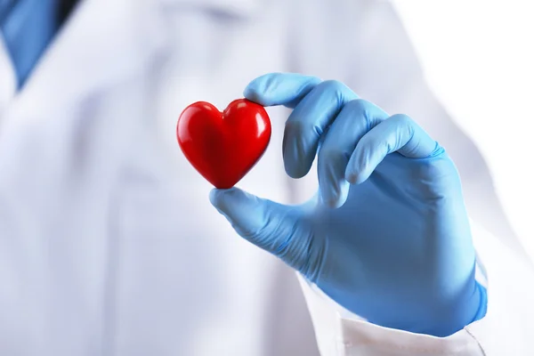 Läkare med stetoskop och litet hjärta i handen på vit bakgrund — Stockfoto