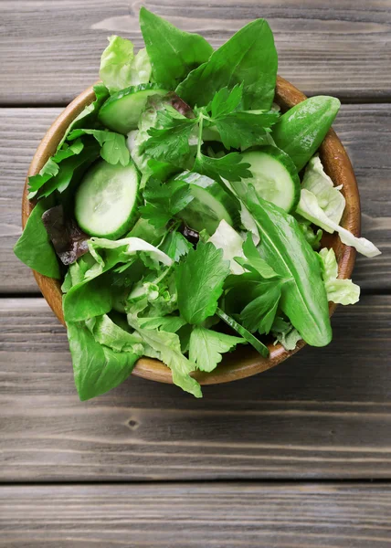 Mix of salad leaves in bowl on wooden planks background — Stock Photo, Image