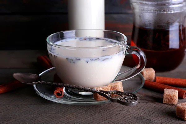 Black tea with milk in glassware and lump sugar on color wooden planks background — Stock Photo, Image