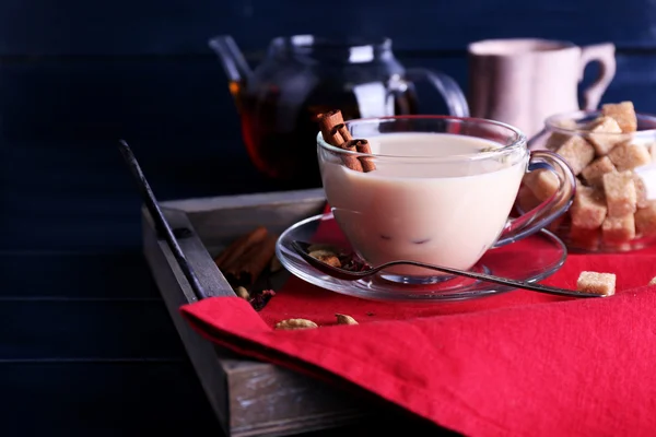 Black tea with milk and lump sugar on wooden tray with napkin and color wooden planks background — Stock Photo, Image