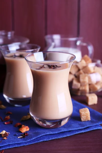 Svart te med mjölk och klump socker och kryddor i glas på färg träplankor bakgrund — Stockfoto