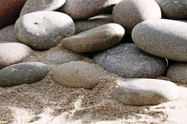Gray sea pebbles on sand background — Stock Photo, Image