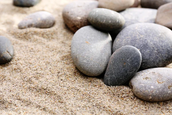 Grijs zee kiezels op zand achtergrond — Stockfoto