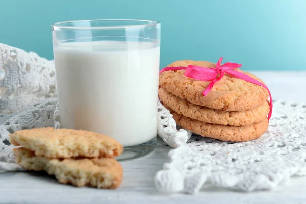 Tasty cookies and glass of milk on color wooden background — Stock Photo, Image