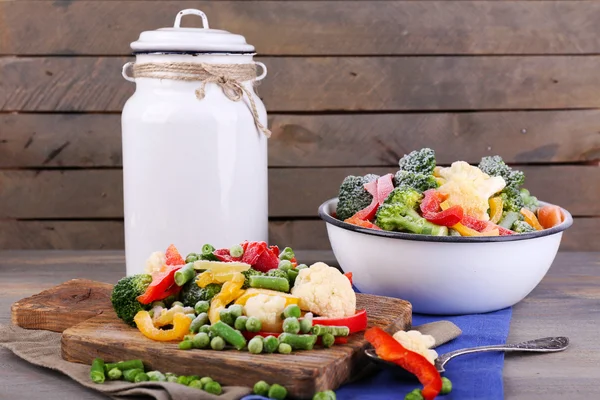 Verduras congeladas sobre tabla de cortar, sobre servilleta, sobre fondo de mesa de madera —  Fotos de Stock