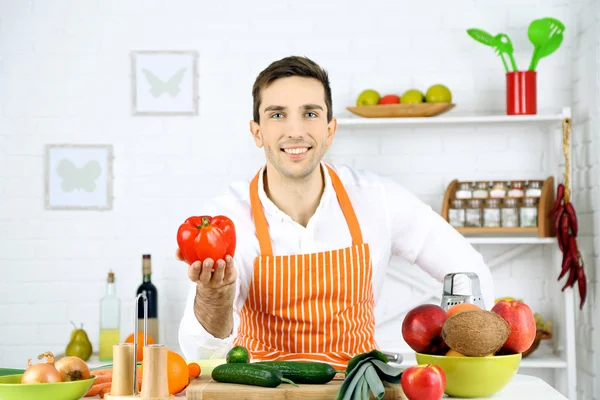 Uomo a tavola con diversi prodotti e utensili in cucina su sfondo bianco a parete — Foto Stock