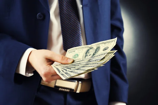 Üzletember ad pénzt a sötét háttér — Stock Fotó