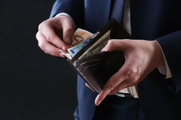 Läder plånbok med pengar i manliga händer på mörk bakgrund — Stockfoto