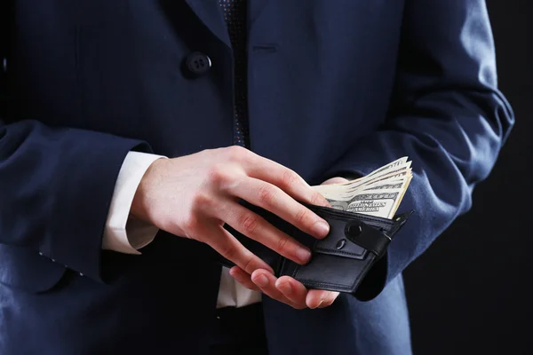 Carteira de couro com dinheiro em mãos masculinas em fundo escuro — Fotografia de Stock