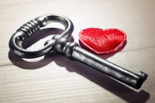 Retro sleutel met rood hart op houten tafel achtergrond — Stockfoto