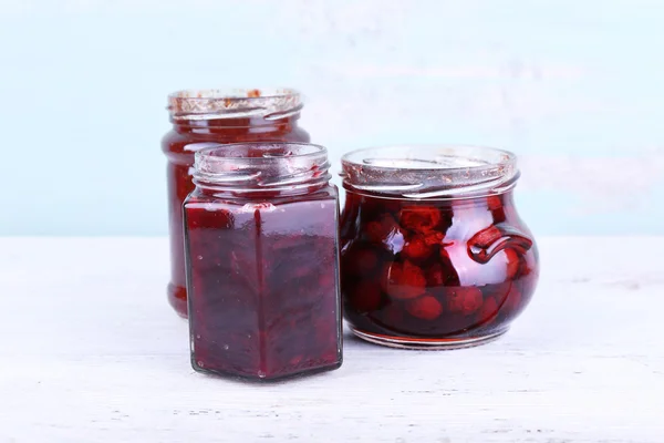 Homemade jars of fruits jam on wooden table and color wall background — Stock Photo, Image