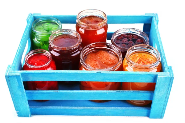 Zelfgemaakte potten van vruchten jam in krat op kleur muur tabelachtergrond — Stockfoto