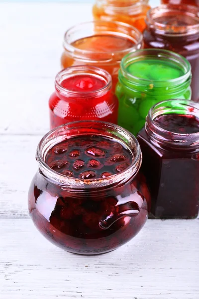 Homemade jars of fruits jam on color wooden planks background — Stock Photo, Image