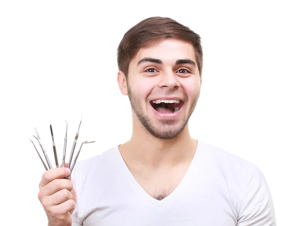Ritratto di giovane uomo sorridente con strumenti dentali isolati su bianco — Foto Stock
