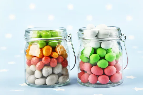 Caramelos multicolores en frascos de vidrio sobre fondo colorido —  Fotos de Stock