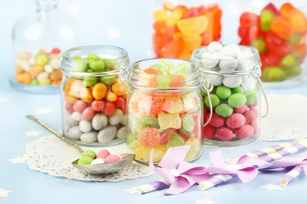 Doces multicoloridos em frascos de vidro sobre fundo colorido — Fotografia de Stock