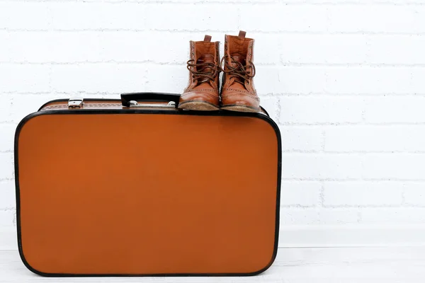 Vintage suitcase with male shoes on wooden floor and brick wall background — Stock Photo, Image