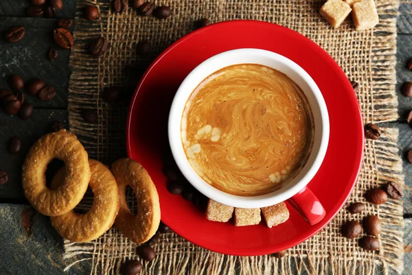 Cangkir kopi dan kue lezat di serbet kain karung, di latar belakang kayu — Stok Foto