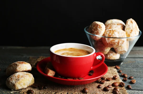 Cangkir kopi dan kue lezat di serbet kain karung, di atas meja kayu, di latar belakang gelap — Stok Foto