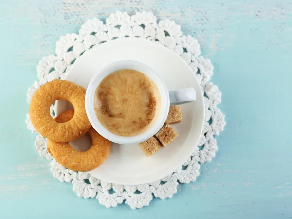 Cup of coffee and tasty cookie on color wooden background — Stock Photo, Image