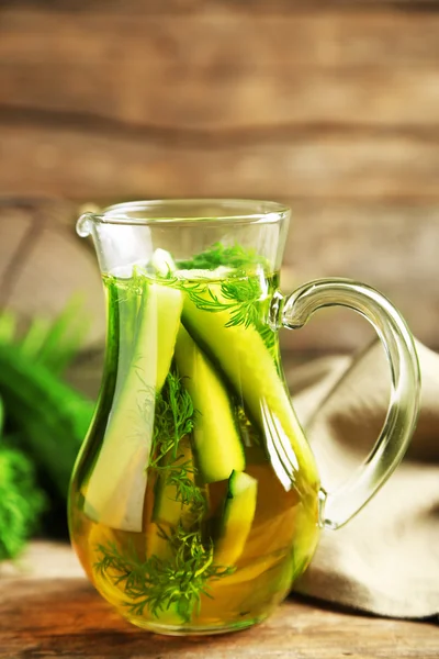 Glass ewer with fresh organic cucumber water on wooden table — Stock Photo, Image