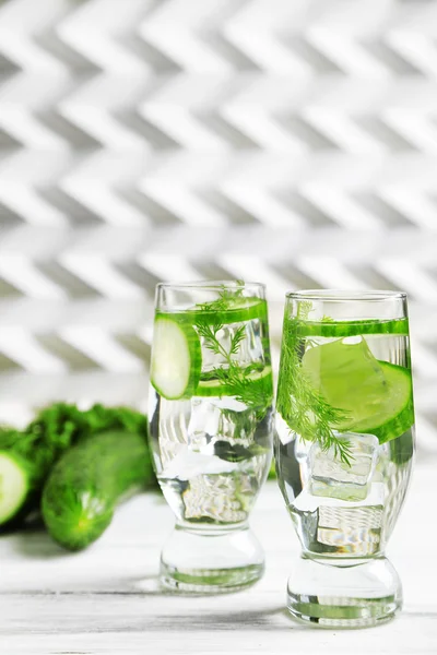 Glasses with fresh organic cucumber water on wooden table, on light background — Stock Photo, Image