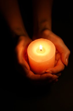 Siyah arka planda kadın ellerinde mum.