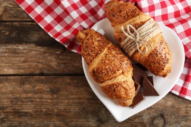Ahşap arka plan üzerinde plaka üzerinde çikolata ile taze ve lezzetli ay çöreği
